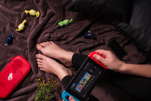 Close-up of a person playing Nintendo Switch with candy and a cozy blanket.