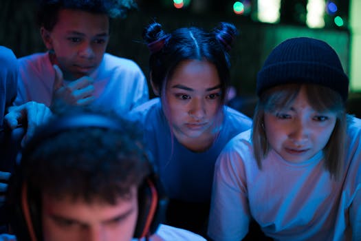 Group of young people intensely focused on a gaming session in a dimly lit indoor environment.