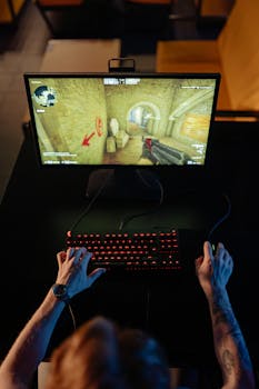Top view of a gamer playing a video game on a computer with glowing keyboard.